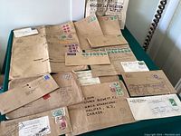 Photo showing a varied collection of aged WWII military envelopes with Canadian postage stamps and censorship labels, plus a wartime newspaper clipping.