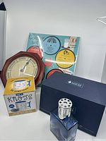 Image showing the blue Lampe Berger with silver top and original navy box, novelty mug in yellow box, day clock, and coaster set in background.