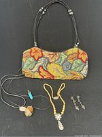 Full lot photo showing vintage floral beaded bag, faux pearl rhinestone necklace, drop earrings, and two pendants on cords.