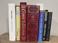 Eight books arranged vertically on a shelf, showing spines including Folio Society editions and other hardcover books.