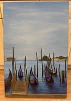 Front view of large signed painting depicting gondolas tied to wooden poles on calm water with buildings in the background.