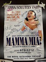Front view of the signed Mamma Mia theatre poster with visible signatures and damage including tears taped at the top.