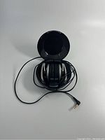 Photo of Sony MDR 710 headphones folded compactly showing black ear pads and coiled cable with 3.5mm plug.