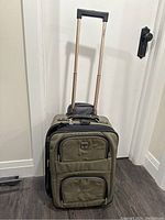 Front view of the Travel Pro carry on suitcase standing upright with telescoping handle extended; shows two front zippered compartments and reinforced edges.