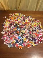 Pile of assorted embroidery threads on cardboard bobbins in various colors spread on a wooden surface.