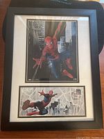 Framed Spiderman print showing Spiderman swinging in city, above first day stamp section.
