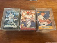 Three individual baseball cards in protective cases featuring Pedro Munoz, Mickey Morandini, and Kevin Sefcik respectively.