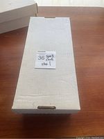 White labeled cardboard box containing sports trading cards with a sticky note saying '36 sports cards box 1'.