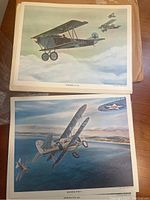 Two vintage color aircraft prints visible, featuring Fokker D.VII biplane and Boeing P-26A monoplane flying over scenic backgrounds with clouds and terrain.