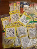 Lot of vintage Aunt Martha embroidery transfer packets in original yellow packaging with pattern illustrations visible. Some sealed, others slightly handled.