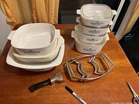 Overview of all items on a wooden table including ceramic casseroles, stands, and pot handle.