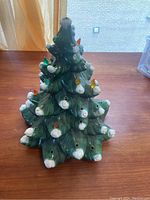 Front view of vintage ceramic Christmas tree showing green branches with white snow tips and colored plastic light inserts.