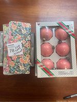 Pink vintage glass ball Christmas ornaments sealed in original box with red and green diagonal stripes.