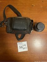 Leather camera case with strap embossed with Pentax logo and separate lens.
