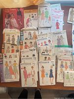 Overview of vintage sewing pattern envelopes on wooden surface showing various brands and designs