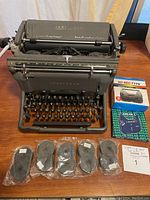 Full view of vintage Underwood manual typewriter with the five sealed black typewriter ribbons and boxed ribbons in front.