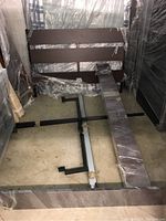 Disassembled bed frame parts laid on floor covered in protective plastic wrapping