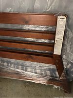 Close-up photo of wooden slats and frame on one side of bunk bed, showing wood grain and plastic wrapping