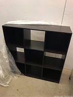 Front view of cubby style cabinet showing 3 columns and 3 rows of open compartments in dark wood.