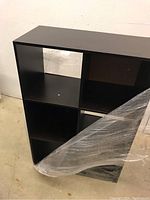 Full perspective photo of the dark wood cubby shelf with six square compartments, showing the construction and finish.