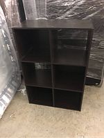 Front view of the dark wood shelf featuring six equally sized horizontal and vertical compartments