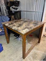 Full view of a square wooden table with a stone pattern veneer top, showing the overall design and legs.
