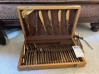 Full view of the open wooden case displaying knives, forks and spoons arranged neatly inside the slots, showing the full set.