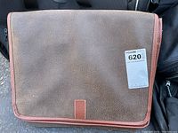 Closed brown leather briefcase showing flap with magnetic snap closures and overall wear.