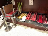 View of the boxed long tapered candles and silver plate candlesticks showing condition and colors.