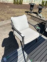 View of the full chair showing beige cushions and metal frame on an outdoor patio.