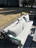 Full view of metal-frame patio sofa with grey cushions on brick patio