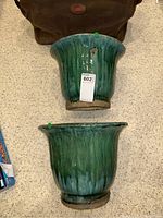 Two large green ceramic planters placed side by side showing the flared rims and glossy glaze surface.
