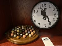View showing wooden circular game board with 40 marble stones and John Cleese silhouette wall clock.