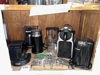 Nespresso coffee maker, Aeroccino frother, coffee grinder container, and extra grill plates displayed inside a wooden shelf.