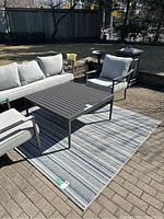 Outdoor blue tone patterned rug under patio furniture on brick surface, showing overall shape and size.