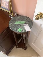 Full view of the plant stand showing the round green marble top with measurement tape indicating 11-inch diameter, positioned in a corner near a door and furniture.