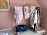 Front view of the metal clothing rack with clothes hung on it and a blue folded item underneath