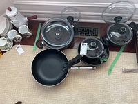 All cookware pieces arranged together showing pots, pans and lids