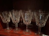 Eight crystal wine glasses displayed in a wooden cabinet