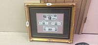 Full view of gold-tone ornate framed display measuring approx 24" W x 20" H containing four U.S. currency notes.