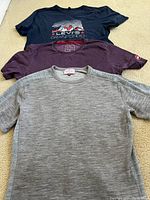 Three men's medium bike t-shirts laid flat showing colour and graphics