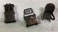Three miniature brass dollhouse furniture pieces: cabinet, dresser with mirror, and chair, shown on white background with penny for scale
