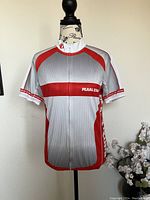 Front view of the Pearl Izumi cycling jersey showing red and gray design, front zipper, and logo on chest.