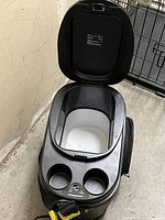 Top view of portable car cooler with lid open showing insulated interior, cup holders, and control panel.
