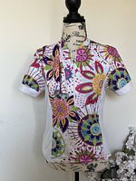 Front view of colorful floral cycling jersey and matching arm warmer on a mannequin.