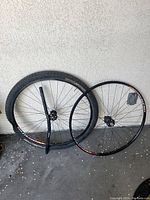 Full view of both 29er wheels, one with tire mounted, placed against wall