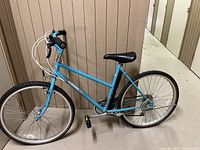 Full left-side view of the blue Mongoose Mixte bicycle showing frame, wheels, handlebars, saddle and pedals