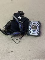 Photo showing vintage Panasonic portable cassette player, wired headphones and waist belt pouch on a grey surface.