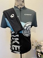Front view of the Capo Bike Monkey cycling jersey with the Pearl Izumi arm warmers draped over the shoulder.