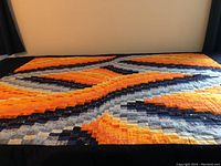 Full view of quilt laid flat showing entire Bargello pattern from blue to orange.